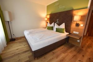 - une chambre dotée d'un grand lit avec des draps blancs et des oreillers verts dans l'établissement Gasthof Lebzelter, à Straßwalchen