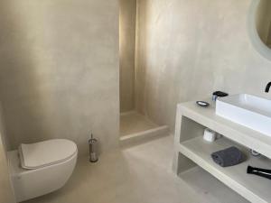 La salle de bains blanche est pourvue de toilettes et d'un lavabo. dans l'établissement Lejardin suites santorini, à Pyrgos