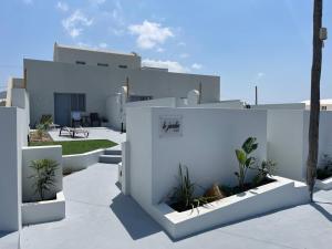 a white house with white walls and plants at Lejardin suites santorini in Pirgos