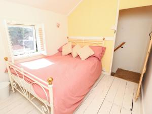 um quarto com uma cama com lençóis cor-de-rosa e uma janela em Foxglove Cottage em Christchurch