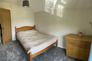 a small bedroom with a bed and a wooden dresser at The Old Barn in St Ives