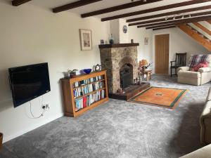 a living room with a television and a fireplace at The Old Barn in St Ives