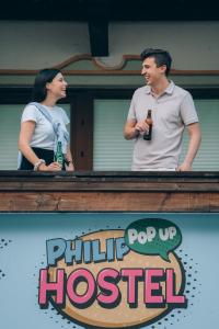 a man and a woman standing in a window with a beer at PhiliPop-Up Hostel in Scharnitz