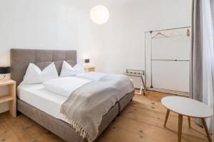Un dormitorio con una gran cama blanca y una mesa en Hotel Greif, en Malles Venosta