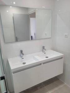 un bagno bianco con due lavandini e uno specchio di Appartement Morgand a Narbonne Altre 7 foto