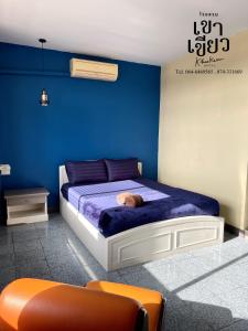 a blue bedroom with a bed with a cat laying on it at KHAO KIEOW Hotel โรงแรมเขาเขียว 