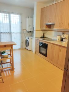 a kitchen with wooden cabinets and a sink and a table at Acogedora casa adosada in Alhendín