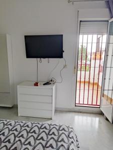 sala de estar con TV de pantalla plana en la pared en Acogedora casa adosada, en Alhendín