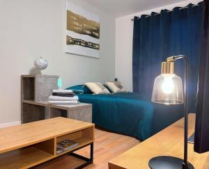 une chambre avec un lit et une table avec une lampe dans l'établissement Le Jockey - SIPCO Immobilier - Centre, à Saint Lo