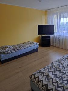a bedroom with two beds and a flat screen tv at Apartament na Wyszyńskiego - mieszkanie w centrum Myszkowa dla firm i nie tylko in Myszków