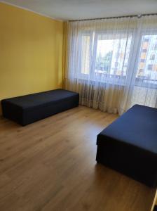a room with two beds and a large window at Apartament na Wyszyńskiego - mieszkanie w centrum Myszkowa dla firm i nie tylko in Myszków +5 photos