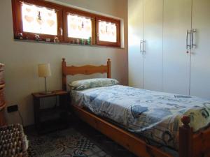 a bedroom with a wooden bed and two windows at Casa ad Issogne chez Piero Vda Issogne-002 in Issogne