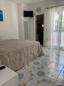 a bedroom with a bed and a tiled floor at Appartamento e piscina condivisa ISIDE in Ischia