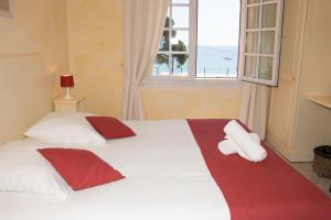 um quarto com uma grande cama branca com toalhas vermelhas e brancas em Hôtel & Spa La Villa em Sainte-Maxime