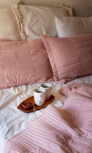 dwa kubki na tacy na łóżku z różowymi poduszkami w obiekcie HOLA Apartamenty Narutowicza w Łodzi
