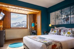 a bedroom with a bed and a large window at Hôtel Courcheneige in Courchevel