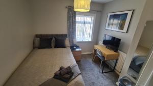 a small bedroom with a bed and a television at Ravenhill Townhouse Belfast in Belfast