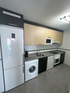 a kitchen with a white refrigerator and a sink at Apartamento Gijon con plaza de garaje. in Gijón