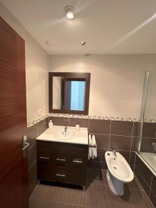 a bathroom with a sink and a toilet and a mirror at Apartamento Gijon con plaza de garaje. in Gijón
