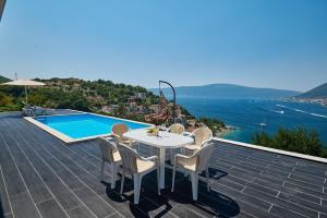 eine Terrasse mit einem Tisch und Stühlen sowie einem Pool in der Unterkunft Villa Bojana in Tivat