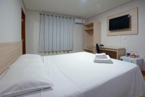 a white bed in a room with a tv at Fênix Hotel Campinas in Campinas