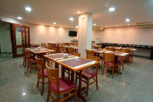 a restaurant with wooden tables and chairs and a piano at Fênix Hotel Campinas in Campinas