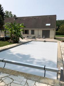 une grande piscine blanche en face d'une maison dans l'établissement Gite de la fontaine Bondrée, à Vernou-sur-Brenne