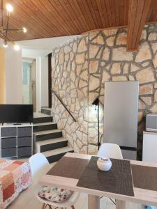 ein Esszimmer mit einem Tisch und einer Steinmauer in der Unterkunft Apartment Kiwi in Rabac
