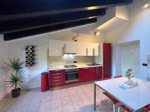 uma cozinha com armários vermelhos e uma mesa branca em Piuma apartment em Gorizia