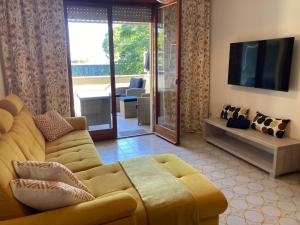 ein Wohnzimmer mit einem gelben Sofa und einem TV in der Unterkunft Grado-Pineta a Mare in Grado-Pineta