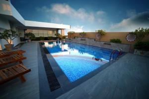 a large swimming pool with blue water in a building at Hotel Blossoms in Tiruchchirāppalli