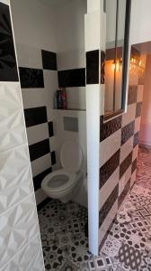 a bathroom with a toilet and a tile wall at Gîte la ruelle in Remiremont