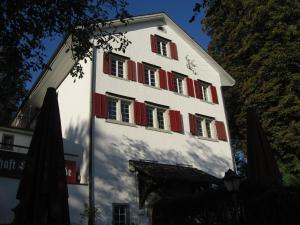 ヴィンタートゥールにあるGasthaus Schlosshaldeの赤いシャッター窓のある白い高い建物