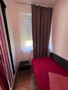 a bedroom with a red bed and a window at Rose No 4 in Friedrichshafen