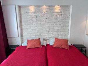 a bed with two red pillows and a brick wall at Rose No 4 in Friedrichshafen