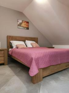a bedroom with a wooden bed with a pink blanket at Chez Claudia in Salazie