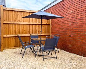 een tafel en stoelen met een parasol op een patio bij Modern 3 Bedroom House, Sleeps 6 - Free Parking & Garden - Opposite Racecourse, Near City Centre & Hospital in Doncaster