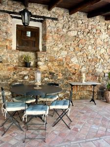 una mesa y sillas frente a una pared de piedra en Masía Can Viver, en Bigues i Riells