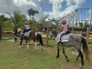 twee kinderen rijden op paarden in een veld bij VILLA GRANDEZZA in Punta Cana