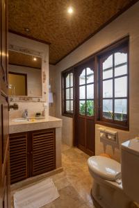 a bathroom with a sink and a toilet and a mirror at Nusa Indah Candidasa in Candidasa