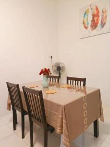 Una mesa con cuatro sillas y un jarrón de flores. en Miri Morsjaya HOMESTAY, en Miri