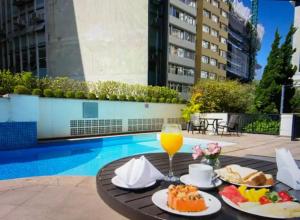 stół z jedzeniem i drinkiem przy basenie w obiekcie Flat incrível próximo a Paulista w São Paulo