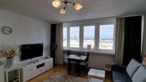 een woonkamer met een televisie en een bureau met een tafel bij Like Home Flat B in Warschau