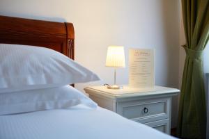 a bed with a table with a lamp on it at Hotel Panorama in Bertinoro