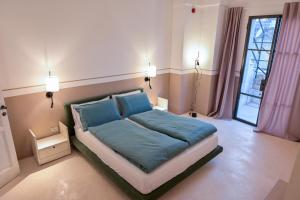 una camera da letto con un letto con lenzuola blu e una finestra di Jrooms - Apulian Home a Tricase