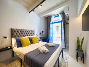 a bedroom with a large bed with yellow and blue pillows at Mandera's Boutique Suites & Dorms in Valletta