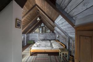 a bedroom with a bed in a wooden attic at Hollóköves Vendégházak in Hollókő