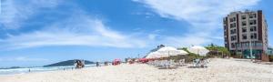 una playa con sillas blancas, un edificio y el océano en Palm Beach Apart Hotel, en Florianópolis