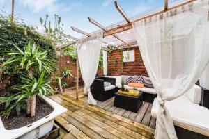 a backyard deck with a pergola and a couch at 2BED Garden house w/Hot Tub, Sauna & Cinema room in London