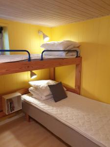 two bunk beds in a room with a yellow wall at St. Strandbygaard in Åkirkeby